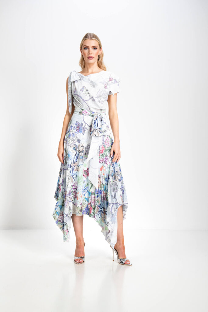 Model wearing a floral asymmetric midi dress with ruffle detailing from the Kevan Jon Mother of the Bride Collection, available at The White Gallery Ramsbottom near Liverpool.