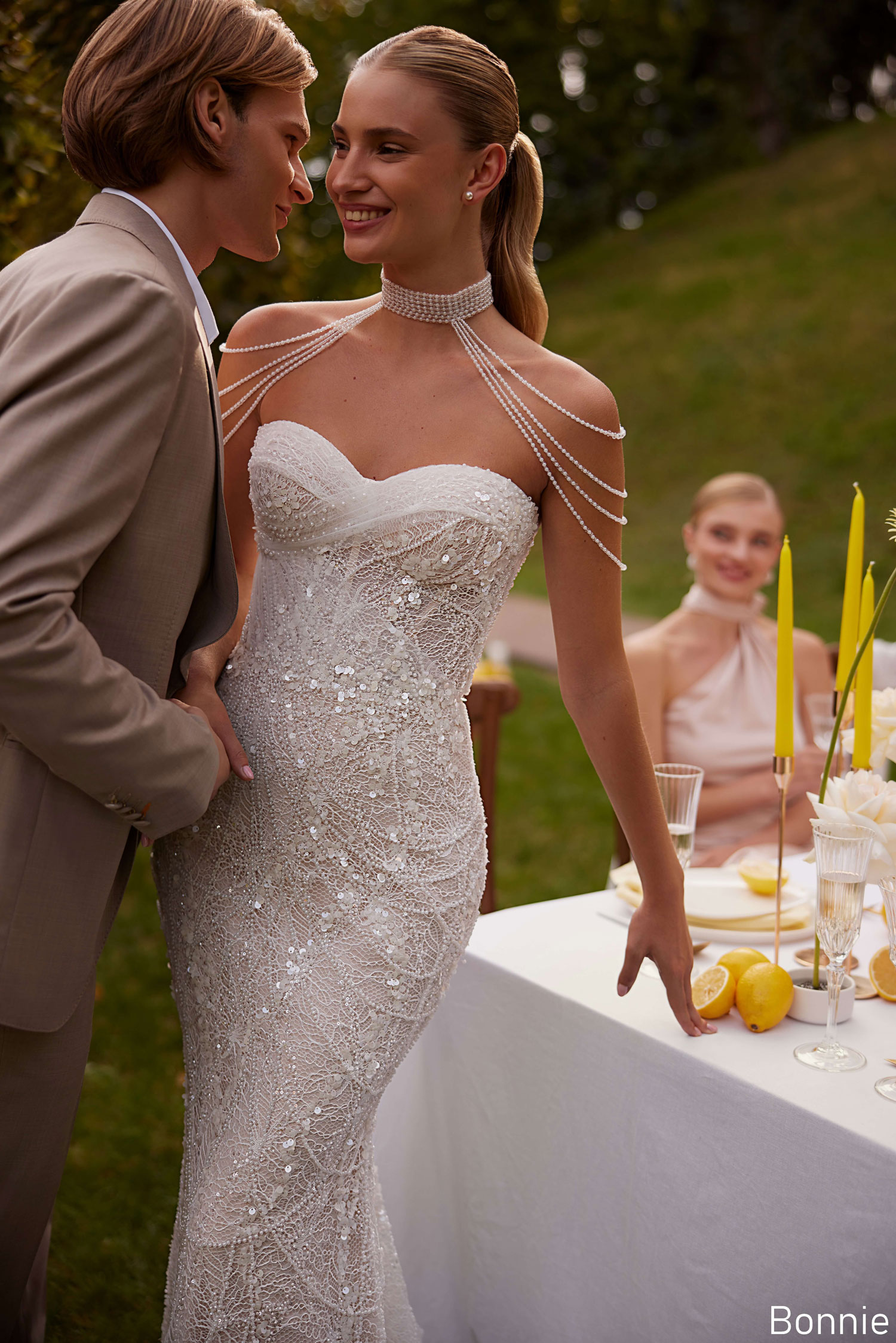 Bride wearing a sequinned strapless wedding dress with pearl shoulder detail, smiling with her partner during an outdoor celebration near Liverpool, from The White Gallery Ramsbottom.